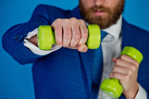 Successful business man holding a heavy dumbbell on blue background