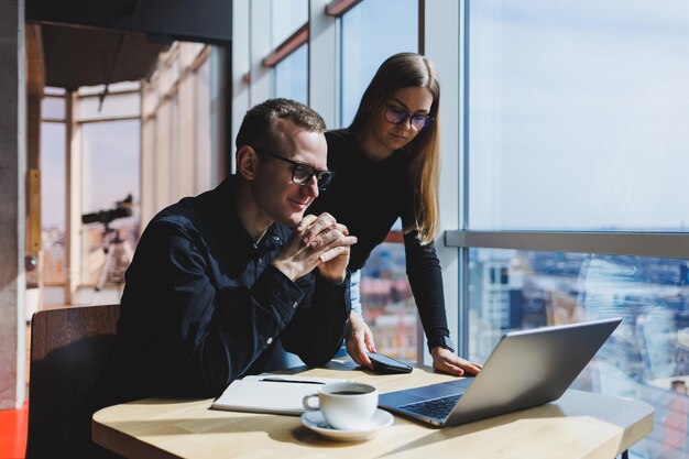 Successful business team male and female colleagues talking at work discussing a new project with a laptop young executives have a friendly conversation cooperate in teamwork in the office