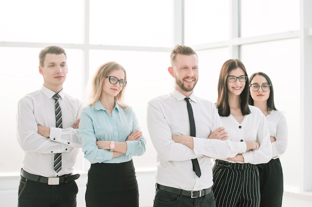 Успешная бизнес-команда, стоящая в ярком офисе. Фотография с копией пространства