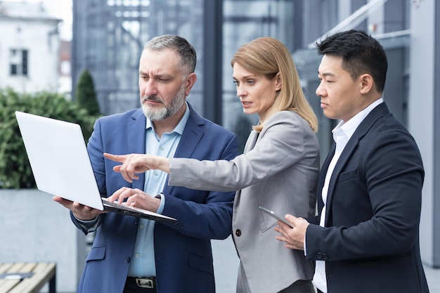 Successful business team three colleagues businessman and businesswoman outside office building