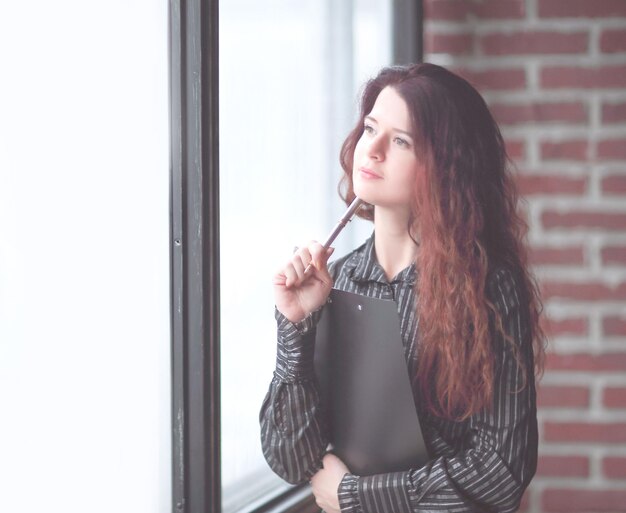 Successful business woman looking out the window of a modern office