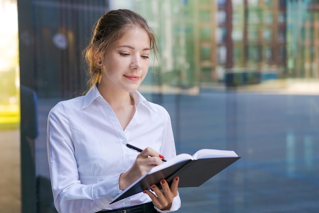 Successful business woman making notes in notebook outdoors in business