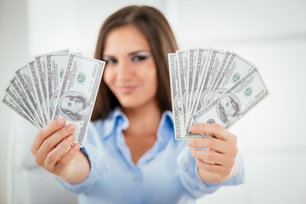 Successful business woman at the office holding money. Selective focus. Focus on the money, on foreground.