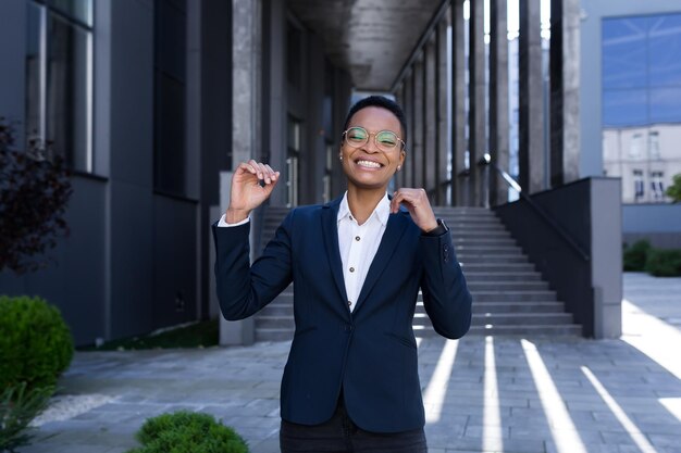 Photo successful business woman rejoices and dances with pleasure african american woman walks near the office