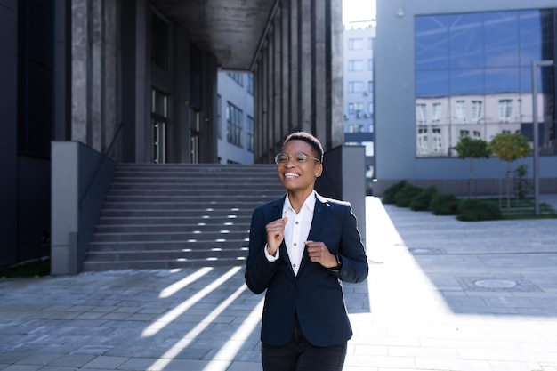 Successful business woman rejoices and dances with pleasure African American woman walks near the office