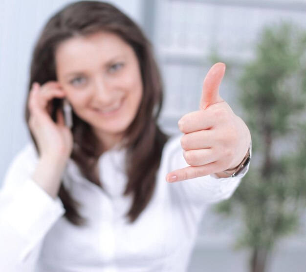 Successful business woman showing thumb upsitting at your Desk