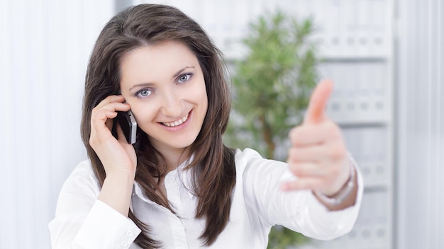 Photo successful business woman showing thumb upsitting at your desk