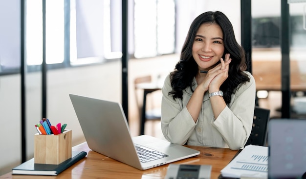 Successful business woman smiling and looking at camera sitting at office desk