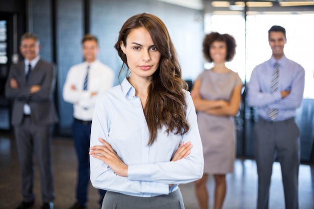 Successful business woman smiling  while her colleagues standing behind him in office