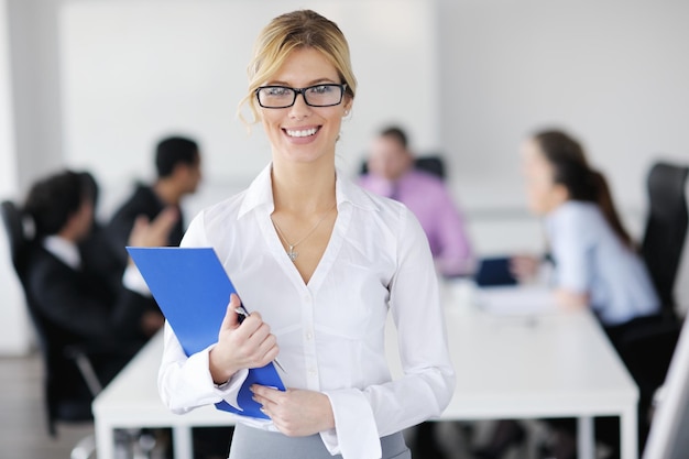 Successful business woman standing with her staff in background at modern bright office