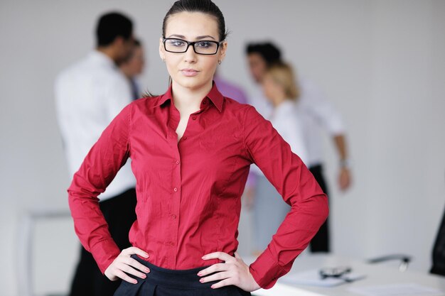 Successful business woman standing with her staff in background at modern bright office