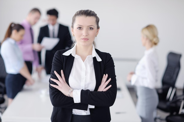 Successful business woman standing with her staff in background at modern bright office