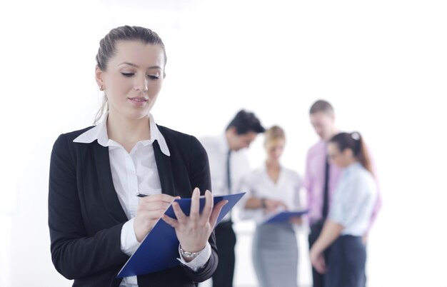 Successful business woman standing with her staff in background at modern bright office