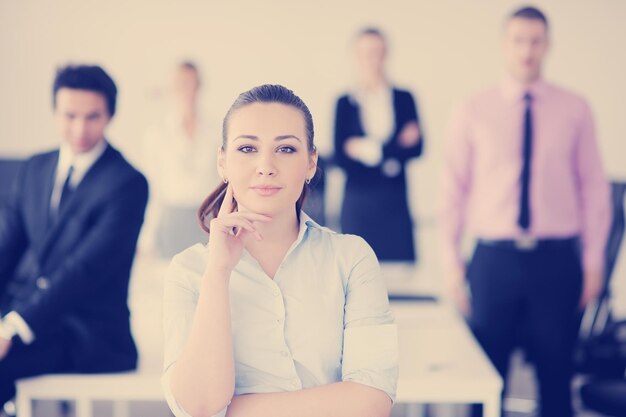 Successful business woman standing with her staff in background at modern bright office