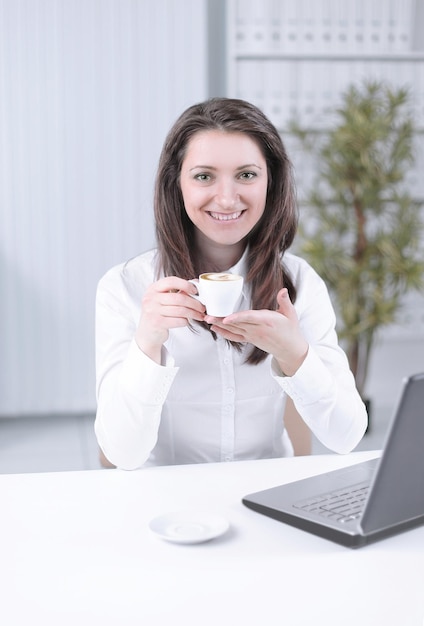 Successful business woman with coffee cup sitting at her desk