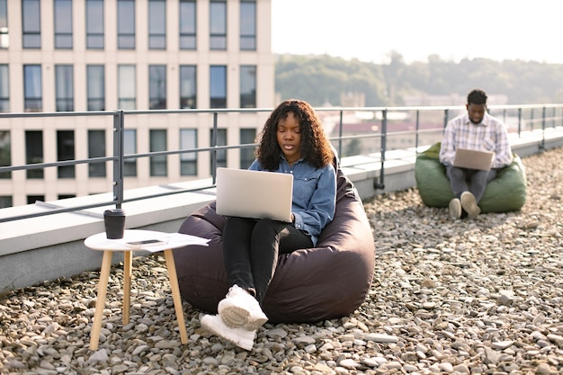 Successful business womansitting at chair bag on roof top and typing on laptop