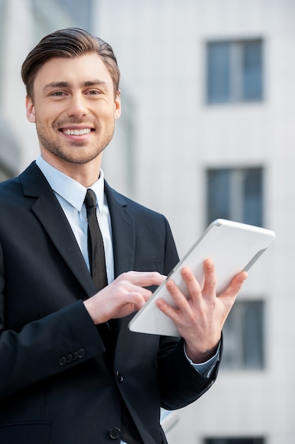 Photo successful businessman. cheerful young men in formalwear holding digital tablet and looking at camera