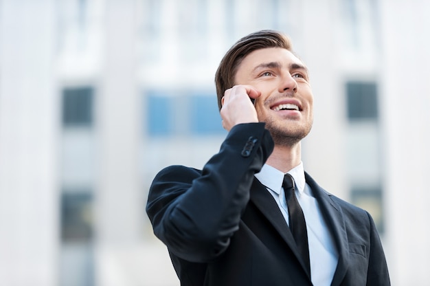 Successful businessman. Cheerful young men in formalwear talking on the mobile phone and smiling