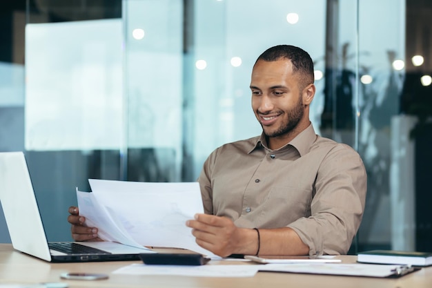 Успешный бизнесмен в офисе читает финансовый отчет латиноамериканец с контрактом