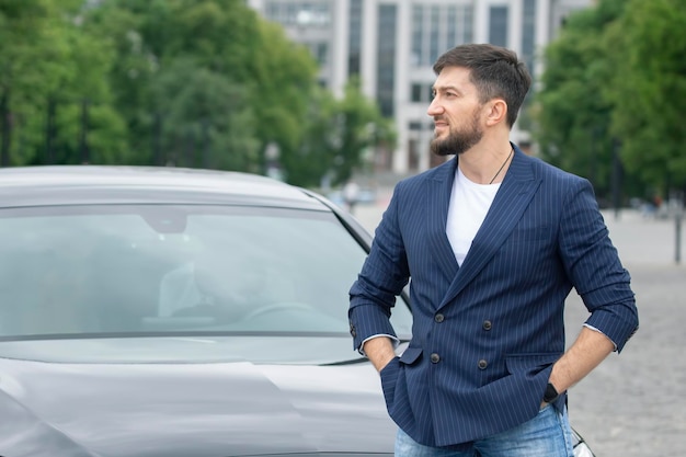 Uomo d'affari di successo è in piedi vicino alla sua auto prestigiosa