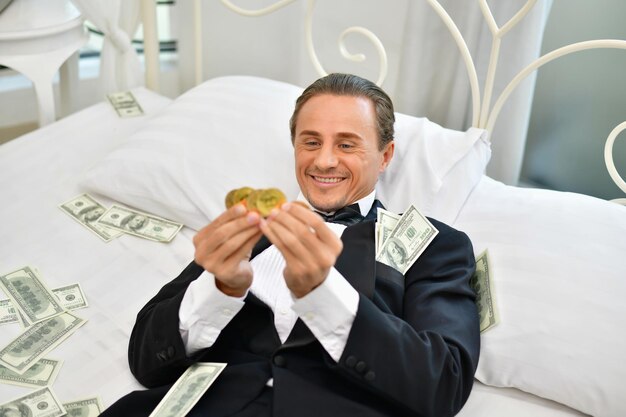 Foto un uomo d'affari di successo sdraiato a letto con dei soldi a casa.