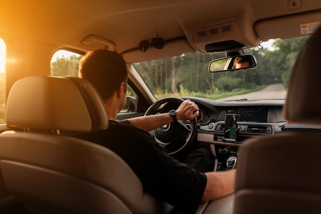 Successful businessman male driver drives a car at sunset