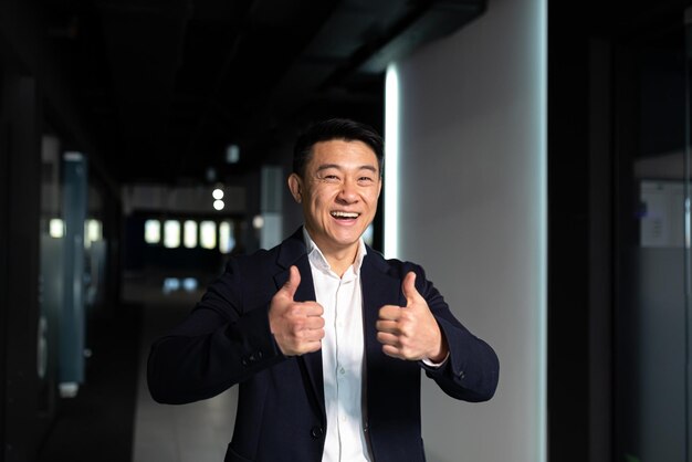 写真 成功したビジネスマンはカメラを見て喜んで親指を立ててサインokアジアのボス幸せと笑い