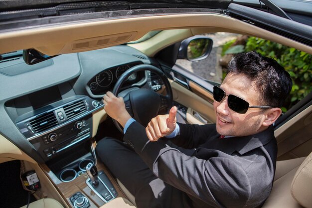 Photo successful businessman shows ok sign in the car