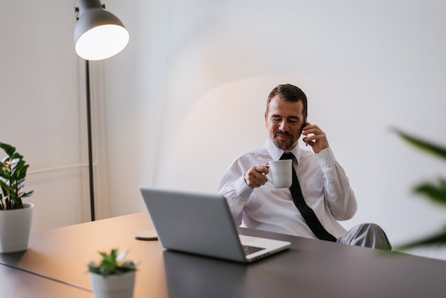 Photo successful businessman sit at his desk while talking on mobile in office