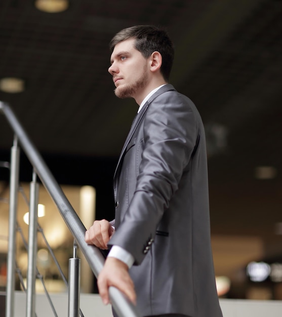 Successful businessman standing on stairs in office building