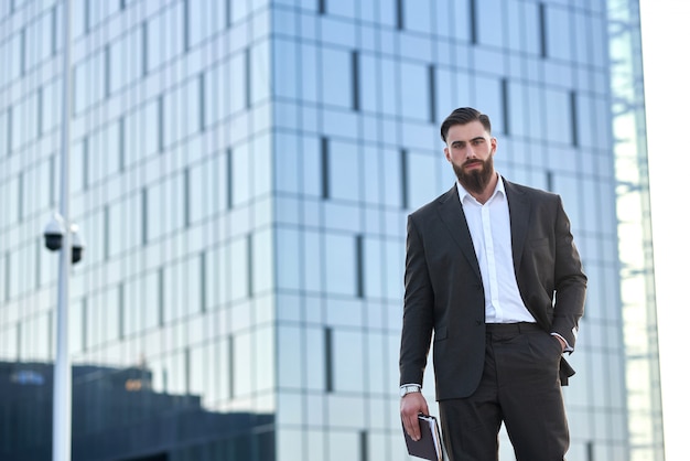 успешный бизнесмен в костюме перед гигантским современным бизнес-центром