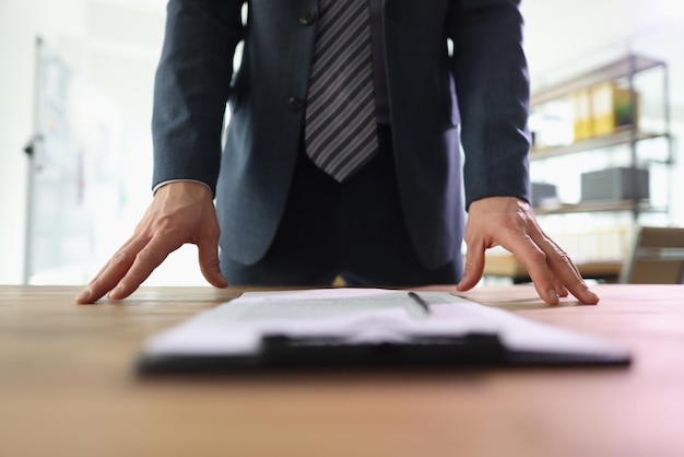 Successful businessman in suit stands above contract papers