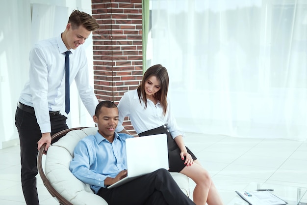 Successful businessman with his assistants in a discussion of the information from the laptop