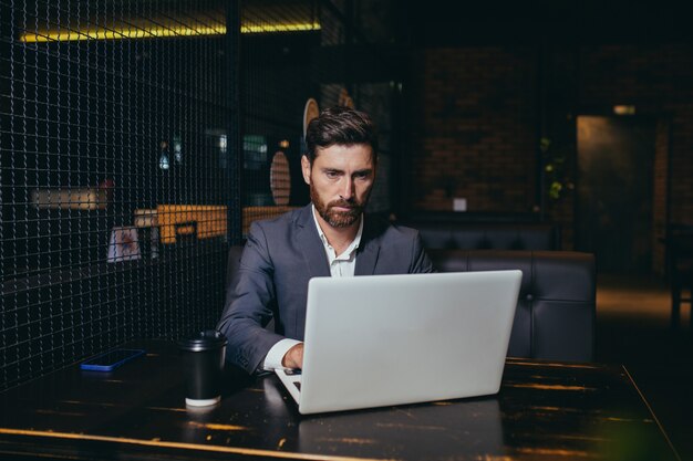 Imprenditore di successo che lavora al computer portatile durante la pausa pranzo seduto nel ristorante dell'hotel