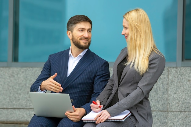 Successful businessmen man and woman with documents and laptop in hands discuss business projects