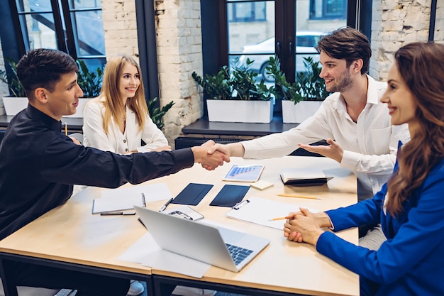 Successful businessmen shaking hands at table in office