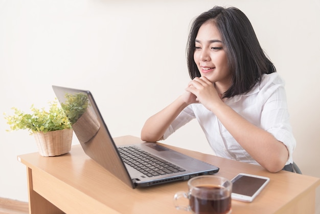 Successful businesswoman is smiling and looking to laptop