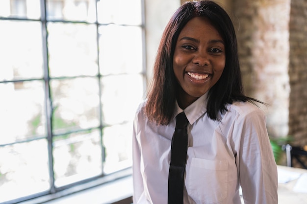 Successful businesswoman with tie smiling in her office sitting on the table