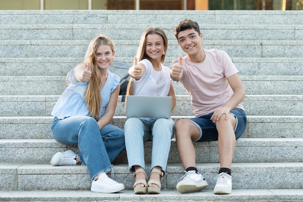 Successful college students gesturing thumbs up or making the ok sign