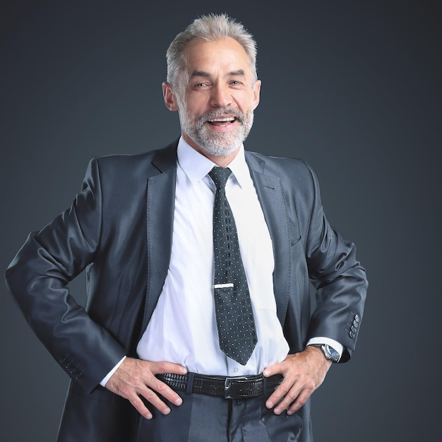 Successful, confident businessman holding his hands at his belt. Isolated on a black background