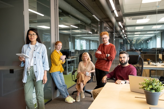 Successful and confident businessmen and businesswomen in casualwear using mobile gadgets while working in large modern office