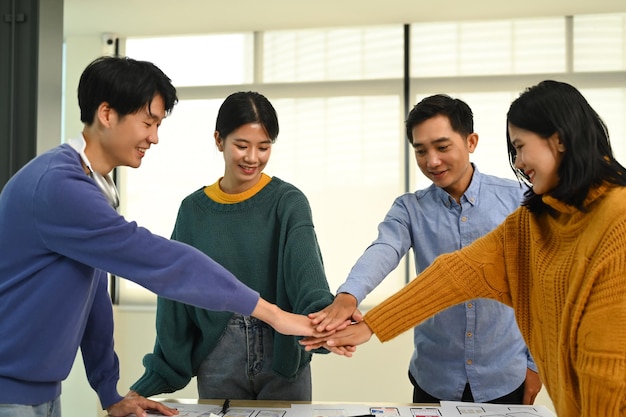 Photo successful creative business team stacking hands together celebrating completion of project