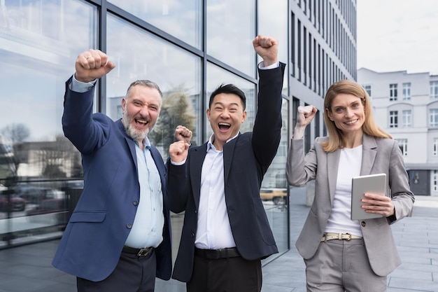 Successful diverse business team three loving men and woman looking at camera and happy celebrating