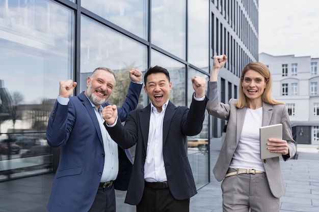 Successo diversi business team tre uomini e donne amorevoli che guarda l'obbiettivo e festeggia felice