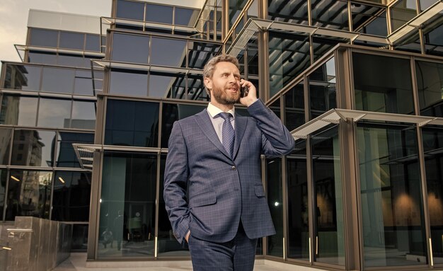Successful entrepreneur in businesslike suit has phone conversation outside the office conversation