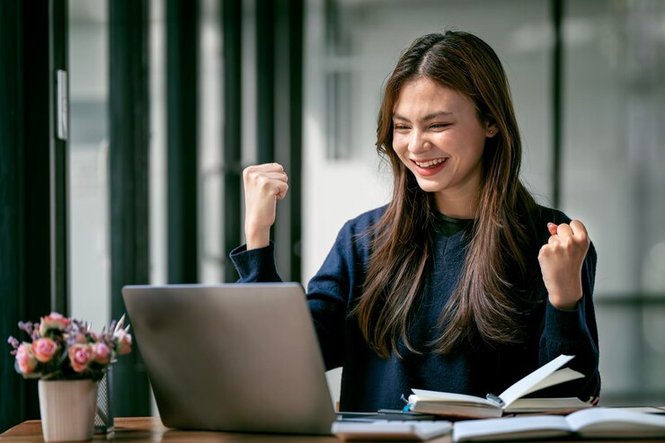Photo successful and exciting caucasian businesswoman young woman excited to win on her laptop computer at work