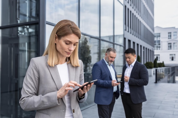 A successful and experienced business woman outside the office building is reading from a tablet