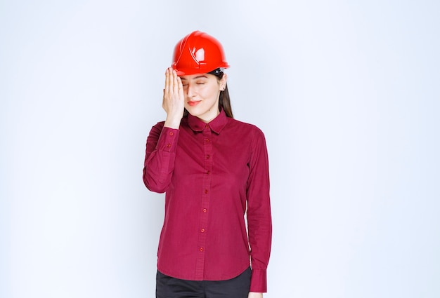 Successful female architect in red hard helmet standing and posing. 