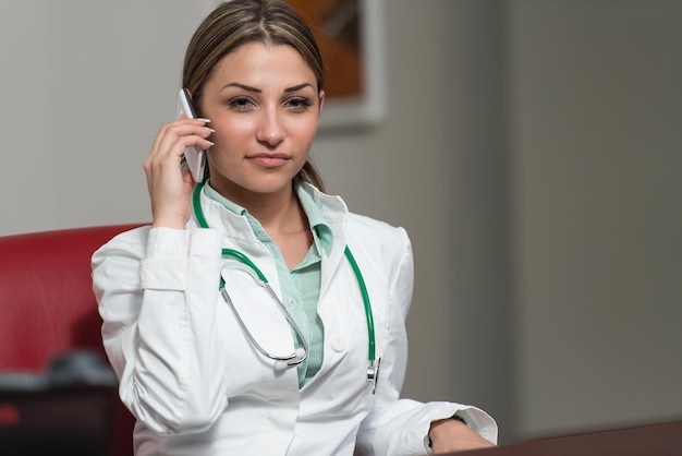 Successful Female Doctor Talking On Cellphone In Office