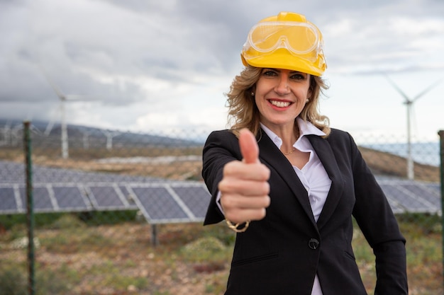 A successful female engineer giving a thumbs up at a solar power plant